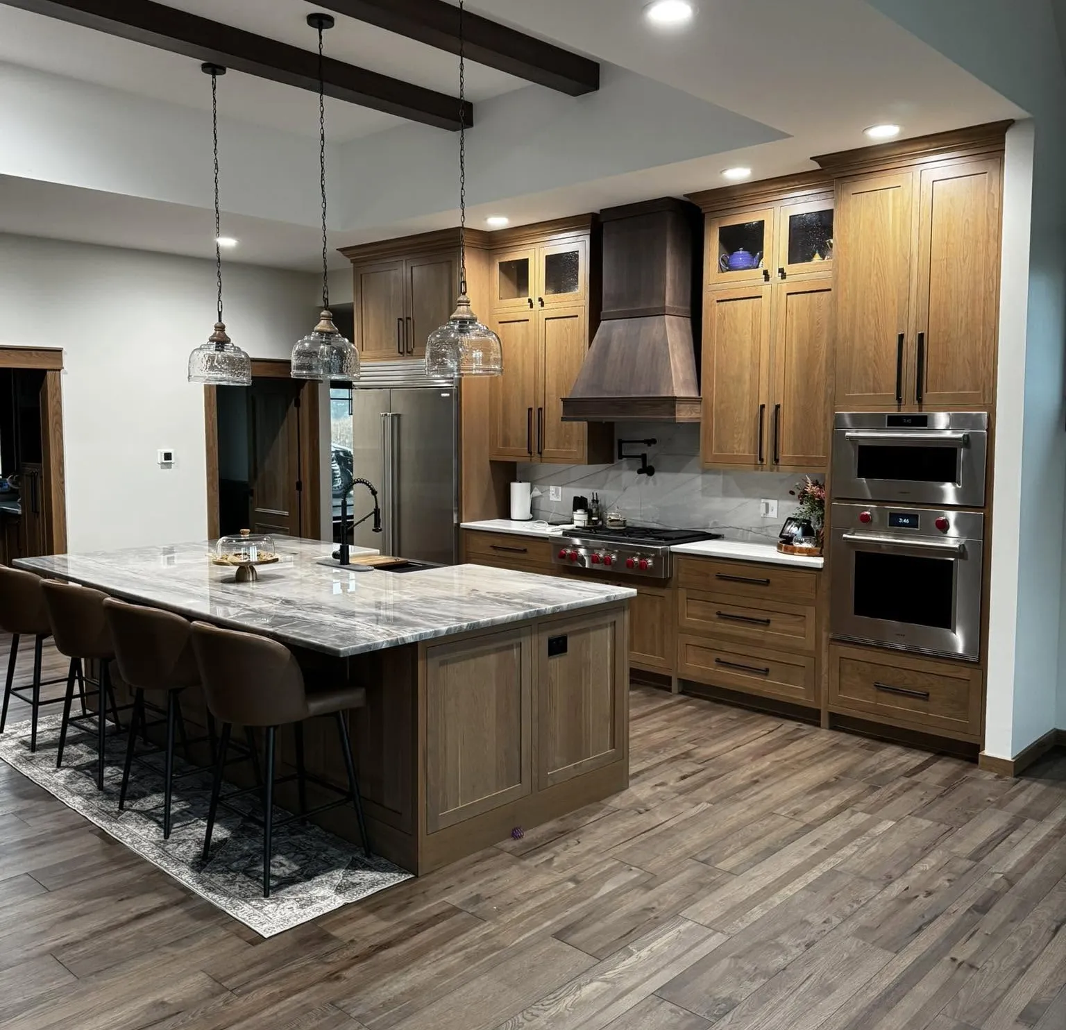 Custom oak kitchen cabinetry with large island, copper range hood, and marble countertops