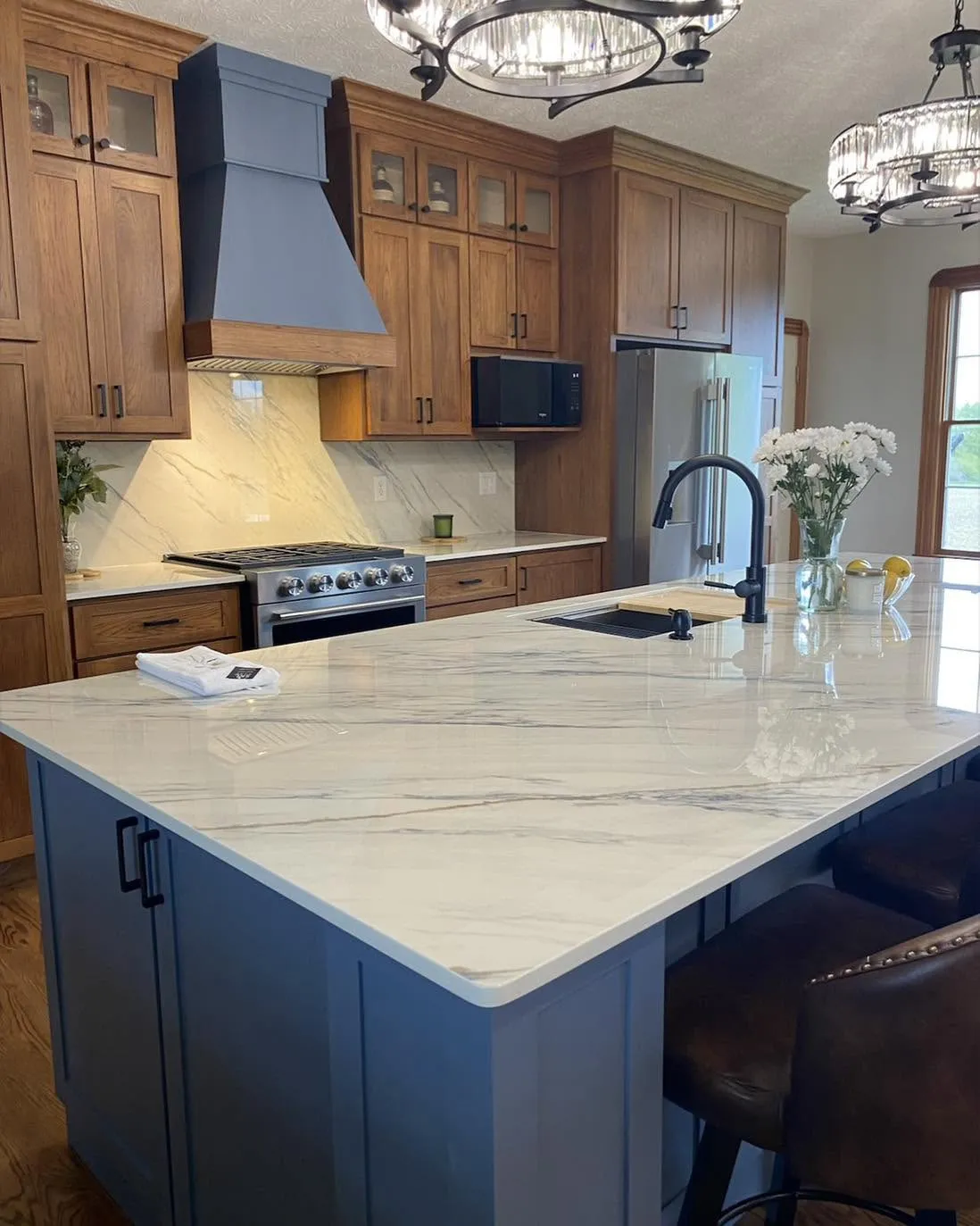 Custom walnut kitchen with slate blue island and quartz waterfall countertop