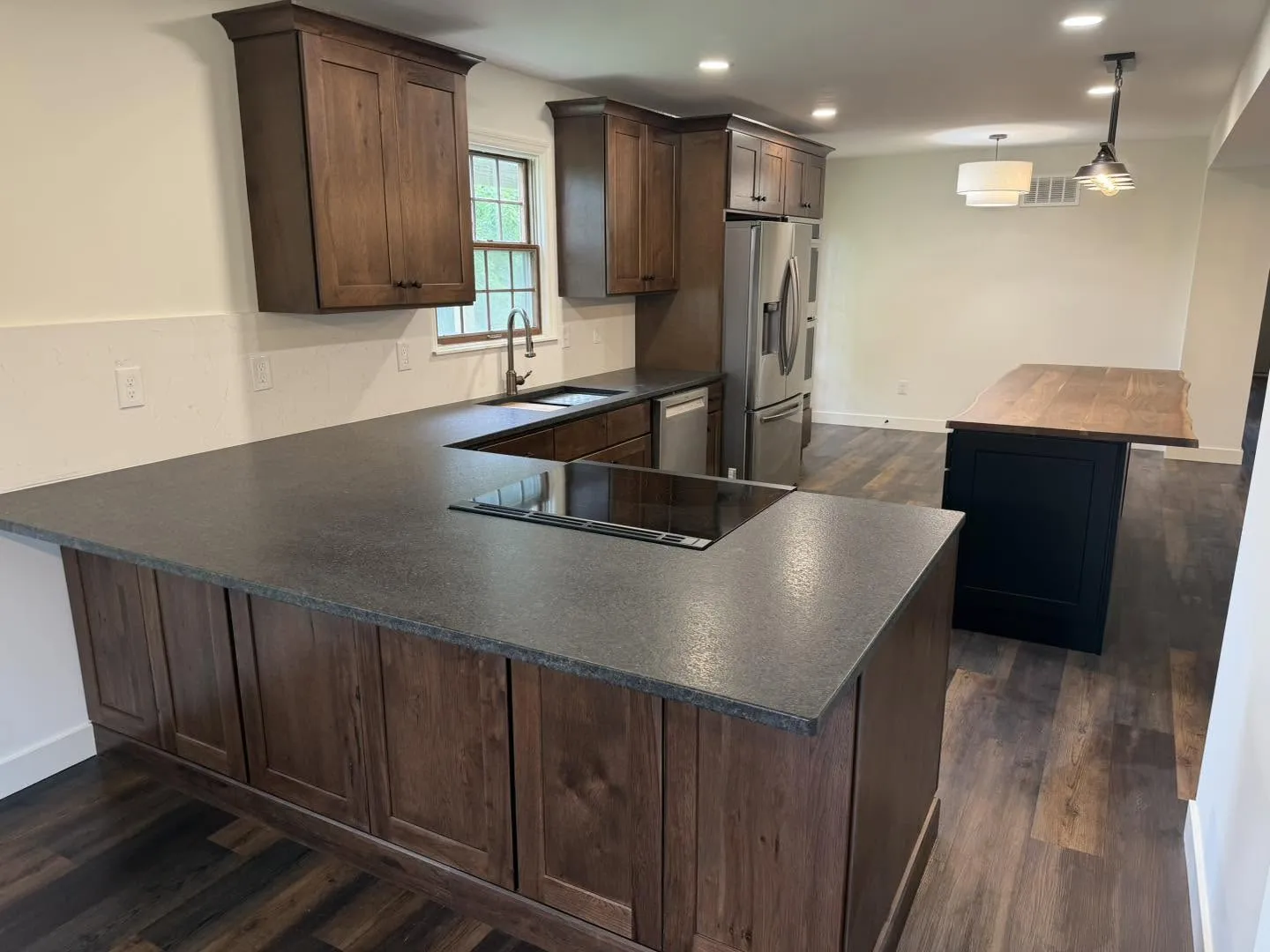 Dark stained cabinetry with honed stone peninsula countertop