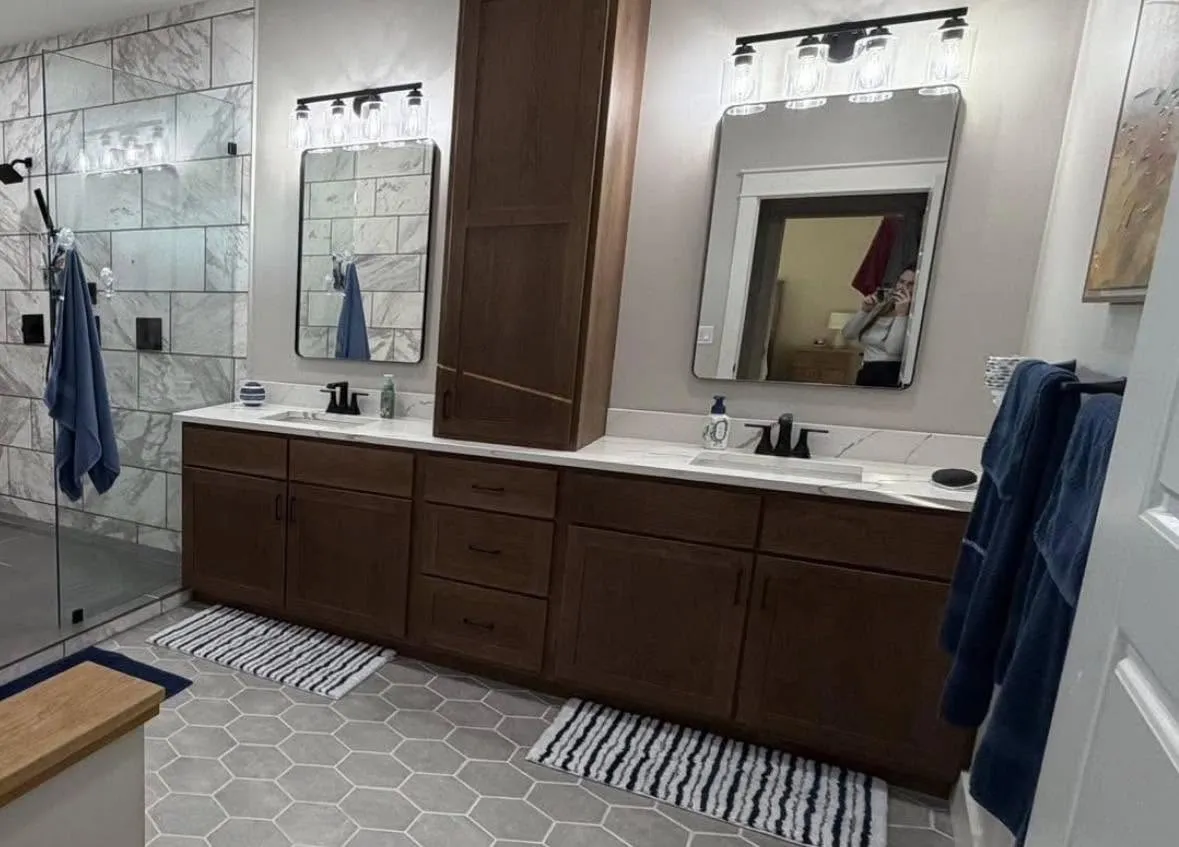 Walnut double vanity with a center tower cabinet and hexagon tile flooring
