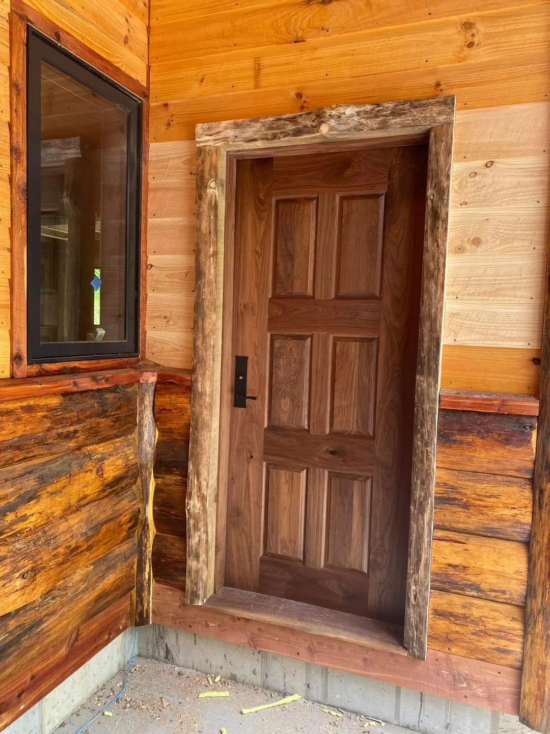Solid walnut entry door with a rustic log-slab frame