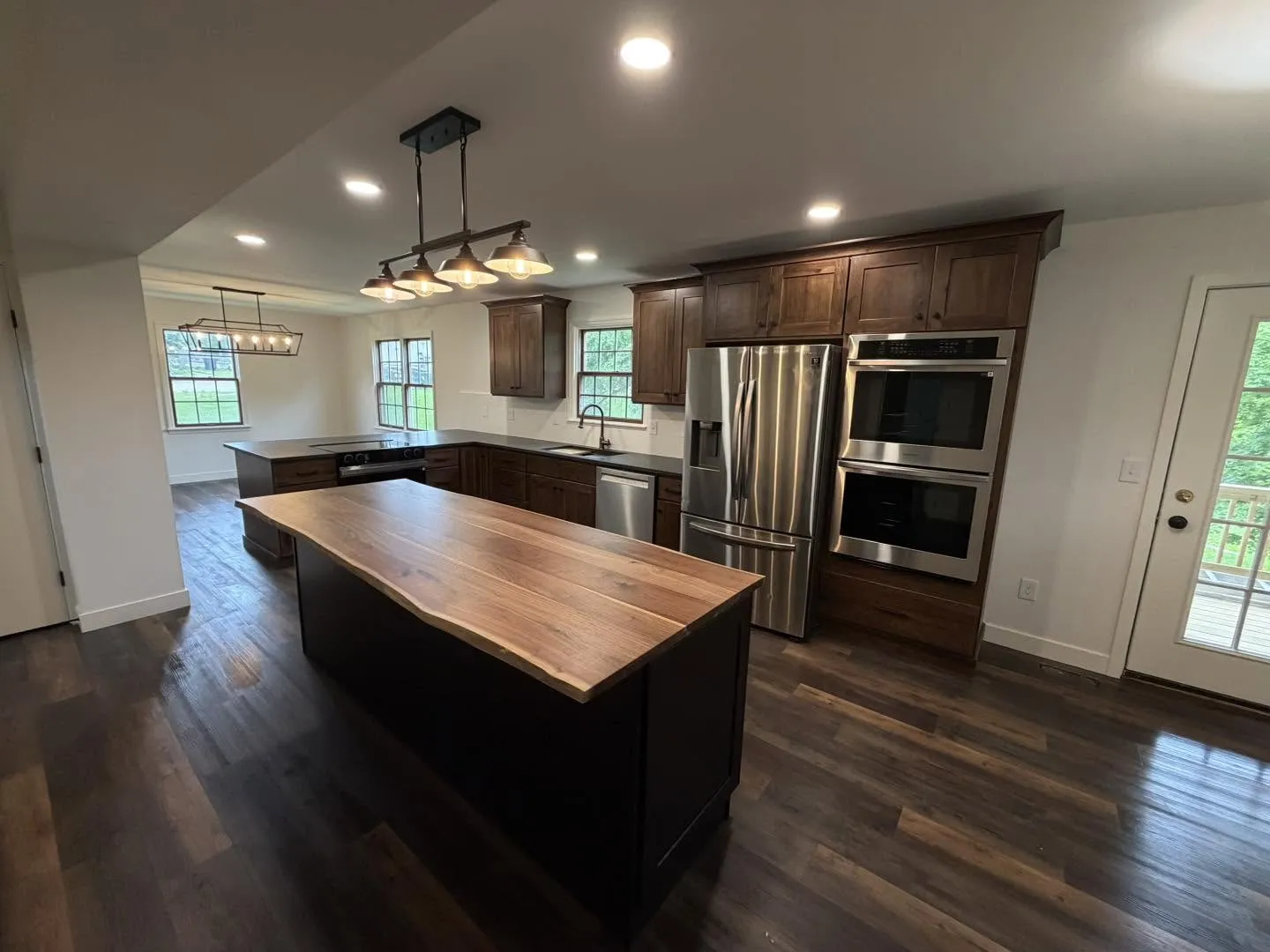 Rich walnut kitchen cabinetry with live-edge island and double wall ovens