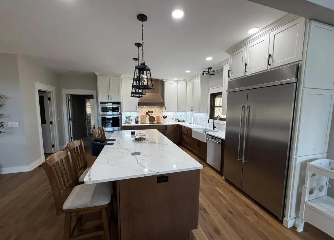White cabinetry kitchen with a stained wood island and herringbone tile backsplash